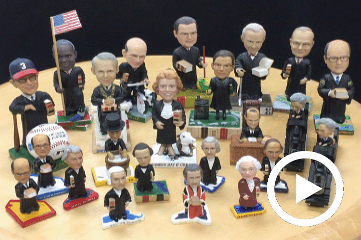 Play button overlaying all 23 Supreme Court bobbleheads, depicting the Justices in miniature bobbling form.